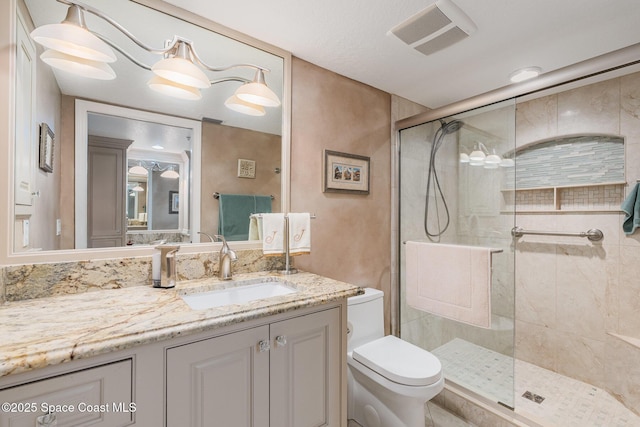 bathroom with vanity, toilet, visible vents, and a stall shower