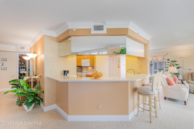 kitchen with crown molding, white appliances, a kitchen breakfast bar, open floor plan, and visible vents