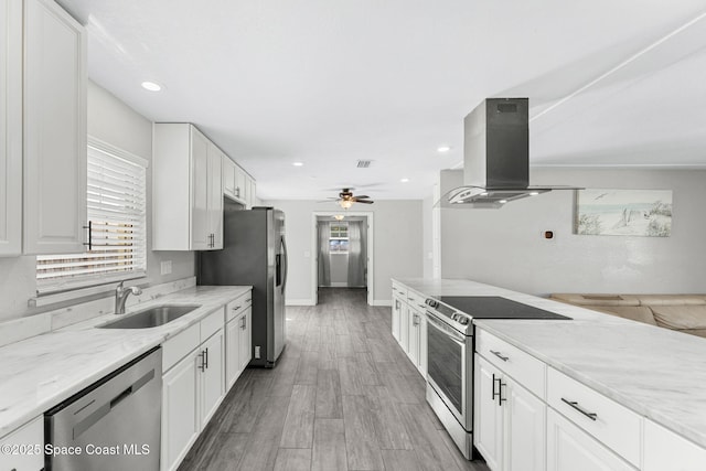 947 Bluewater Dr, Indian Harbour Beach, FL 32937 - kitchen featuring appliances with stainless steel finishes, island exhaust hood, a ceiling fan, white cabinetry, and light stone counters