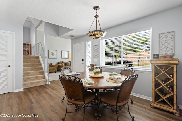 dining room featuring stairway, baseboards, dark wood-style floors, and a textured ceiling