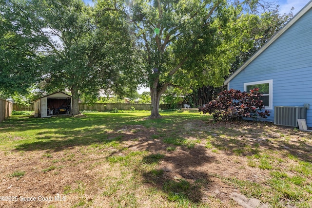 view of yard featuring central air condition unit, an outdoor structure, a fenced backyard, and a storage shed