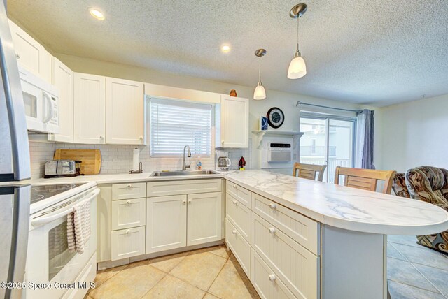kitchen with decorative backsplash, a sink, light countertops, a peninsula, and white appliances