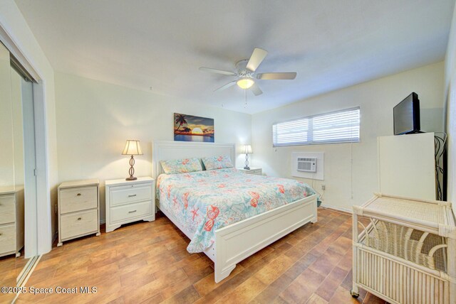 bedroom with an AC wall unit, light wood-style flooring, ceiling fan, and a closet