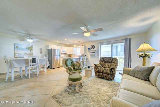 living area with light tile patterned floors, ceiling fan, a wall mounted AC, and a textured ceiling
