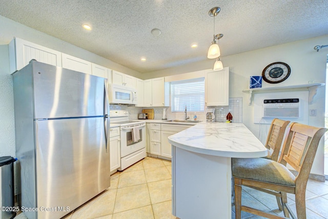 kitchen with decorative backsplash, a peninsula, white appliances, a textured ceiling, and a sink