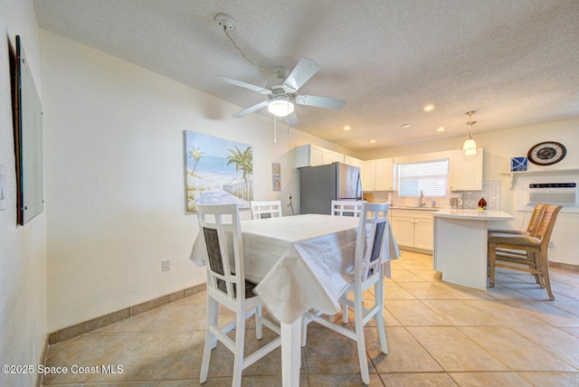 dining space with baseboards, a textured ceiling, and light tile patterned floors