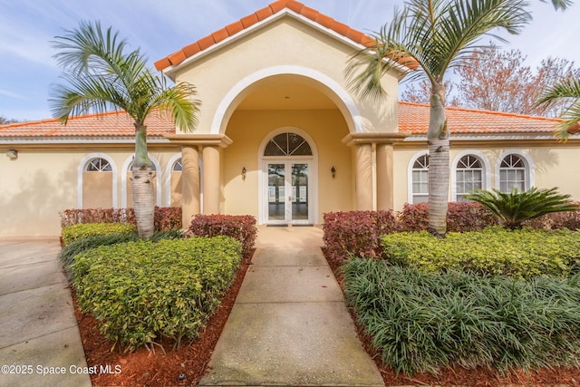 881 Glen Abbey Way, Melbourne, FL 32940 - doorway to property featuring a tiled roof, stucco siding, and french doors