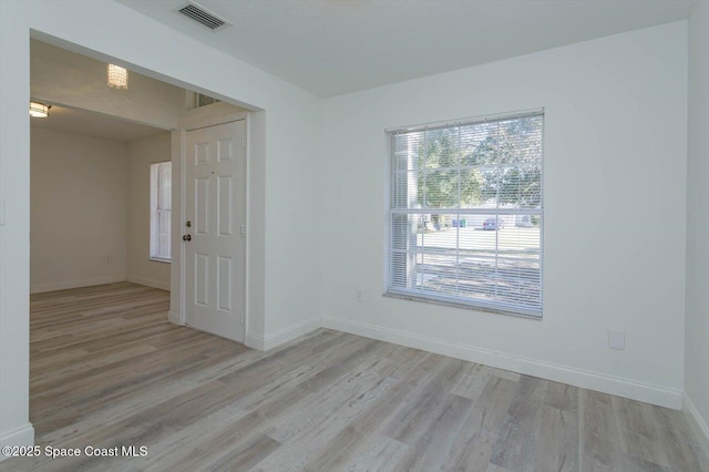 empty room featuring baseboards, wood finished floors, and visible vents
