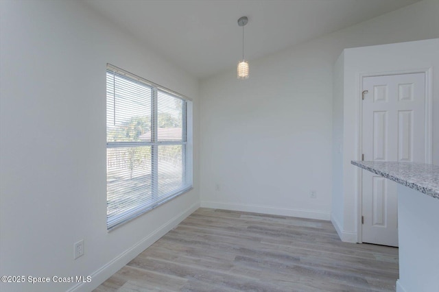 unfurnished dining area with baseboards and light wood-style flooring