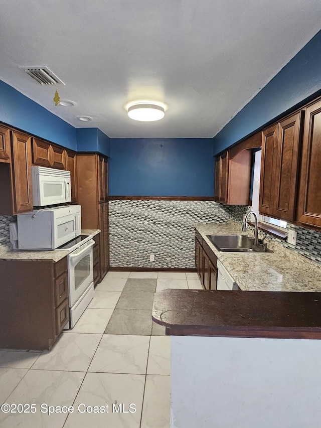 kitchen with a peninsula, visible vents, a sink, and white microwave