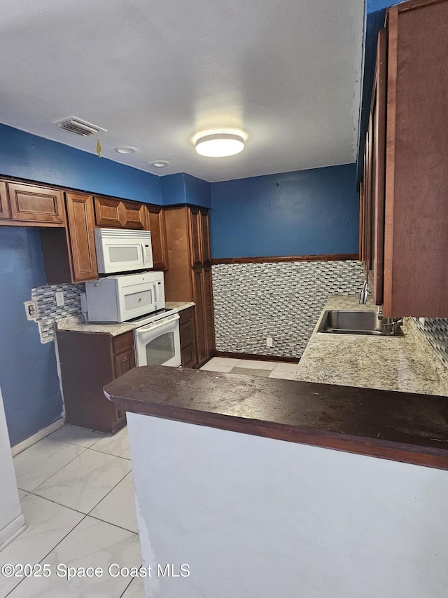 kitchen featuring a sink, white microwave, a peninsula, and visible vents