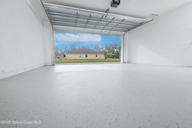 garage with concrete block wall and a garage door opener