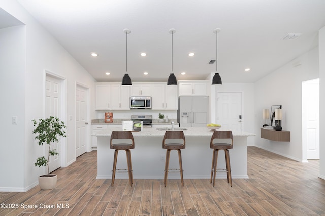 kitchen with light wood-style floors, stainless steel appliances, a large island, and white cabinetry