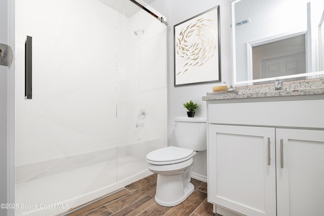 bathroom with visible vents, a shower stall, wood finish floors, vanity, and toilet