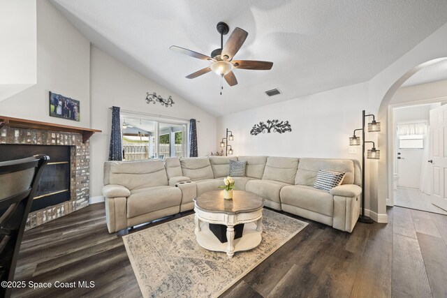 944 Osprey Ln, Rockledge, FL 32955 - living area featuring a brick fireplace, arched walkways, a ceiling fan, dark wood-type flooring, and vaulted ceiling