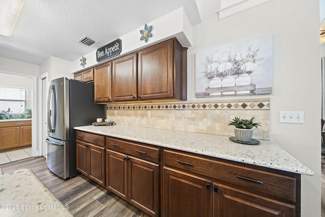 944 Osprey Ln, Rockledge, FL 32955 - kitchen featuring decorative backsplash, light wood-type flooring, light stone countertops, freestanding refrigerator, and a textured ceiling