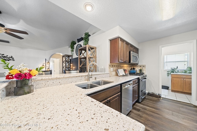 944 Osprey Ln, Rockledge, FL 32955 - kitchen featuring stainless steel appliances, a sink, arched walkways, light stone countertops, and dark wood-type flooring