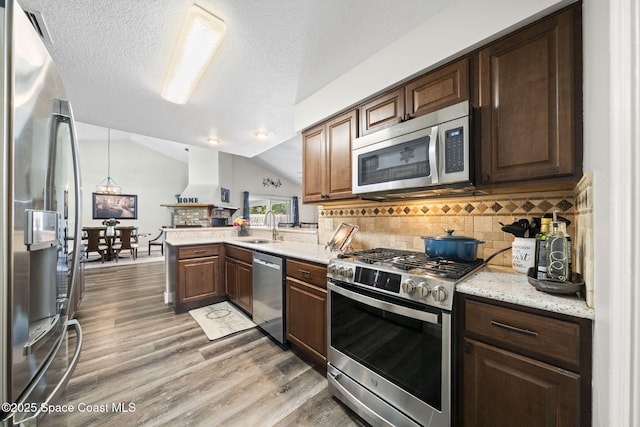 944 Osprey Ln, Rockledge, FL 32955 - kitchen with stainless steel appliances, a sink, light wood-style floors, decorative backsplash, and vaulted ceiling