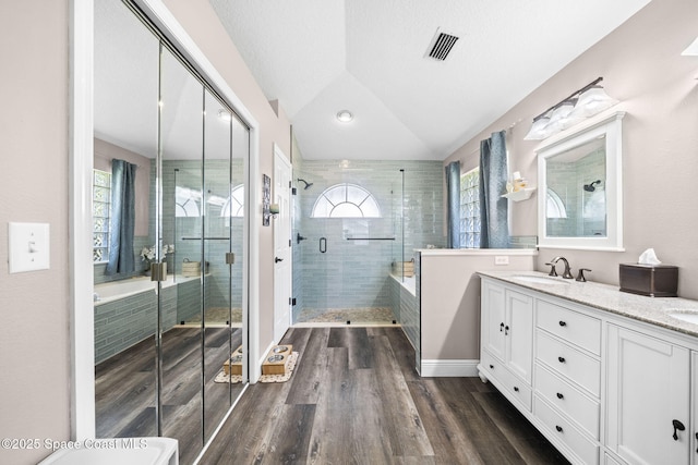 944 Osprey Ln, Rockledge, FL 32955 - bathroom featuring a stall shower, double vanity, wood finished floors, a tub to relax in, and vaulted ceiling