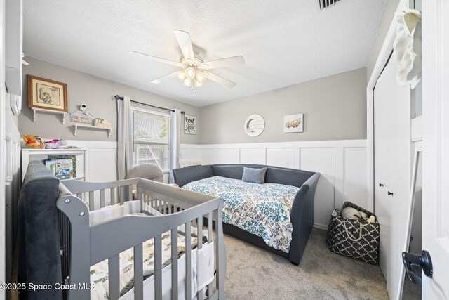 944 Osprey Ln, Rockledge, FL 32955 - bedroom with carpet flooring, a textured ceiling, a wainscoted wall, and ceiling fan