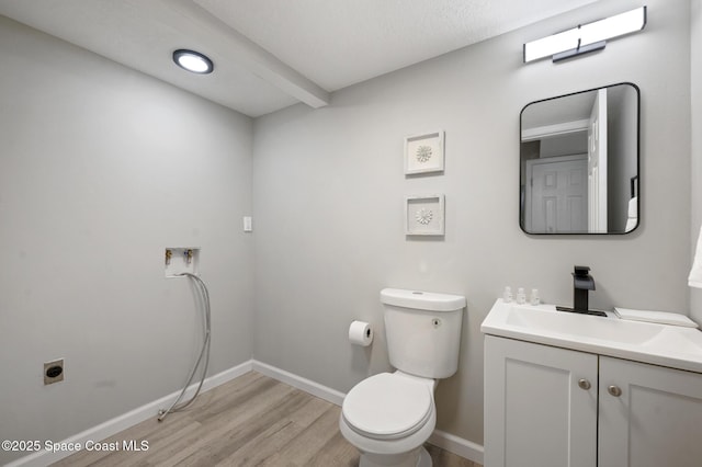 bathroom featuring toilet, baseboards, wood finished floors, and vanity