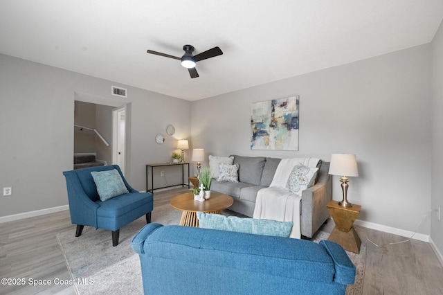living room featuring ceiling fan, stairs, wood finished floors, and visible vents