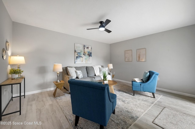 living area featuring baseboards, a ceiling fan, and wood finished floors
