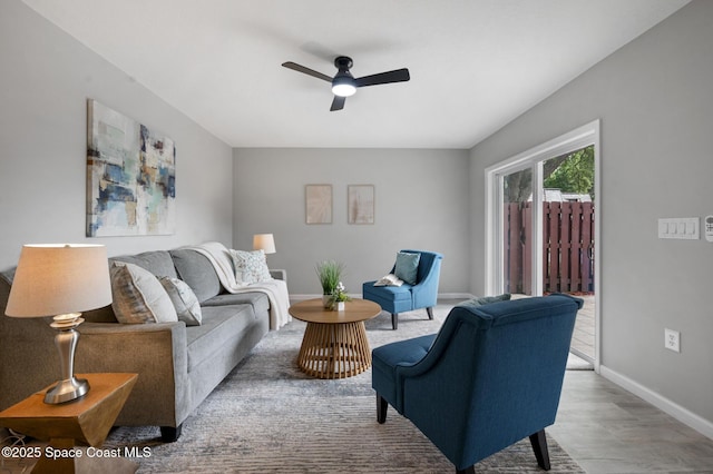 living room featuring baseboards, ceiling fan, and wood finished floors