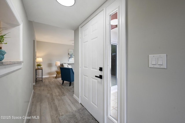 hall featuring baseboards and light wood-type flooring