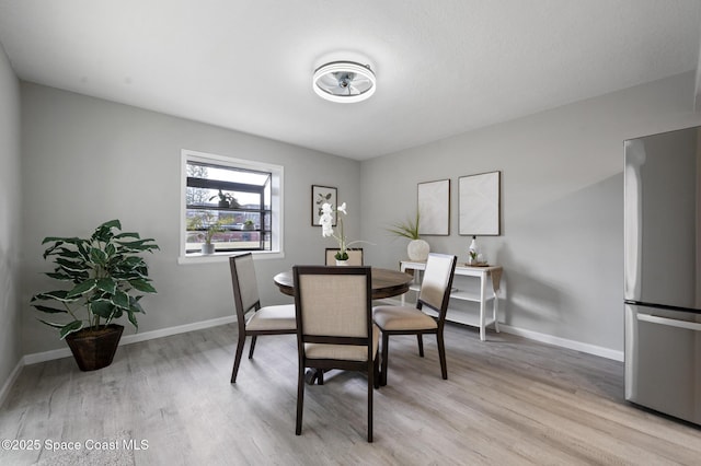 dining area with baseboards and light wood-style flooring