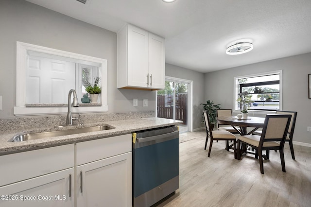 kitchen with a sink, white cabinetry, baseboards, light wood-type flooring, and dishwashing machine