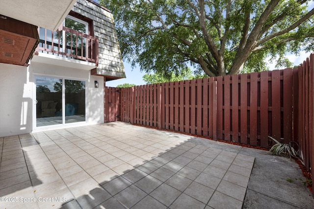 view of patio featuring a fenced backyard and a balcony