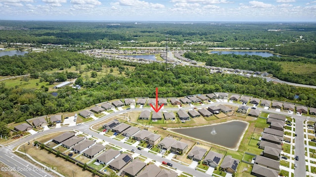 aerial view of property's location featuring a heavily wooded area, a nearby body of water, and nearby suburban area