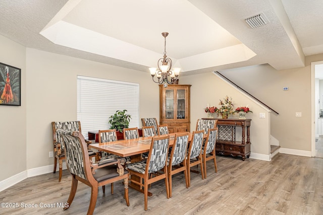 7703 Windover Way, Titusville, FL 32780 - dining space with a chandelier, light wood-style flooring, baseboards, a tray ceiling, and visible vents