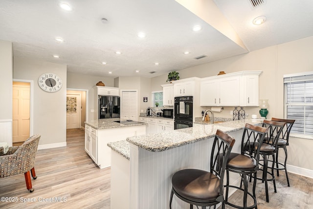 7703 Windover Way, Titusville, FL 32780 - kitchen featuring visible vents, a kitchen island, baseboards, light wood-style flooring, and black appliances