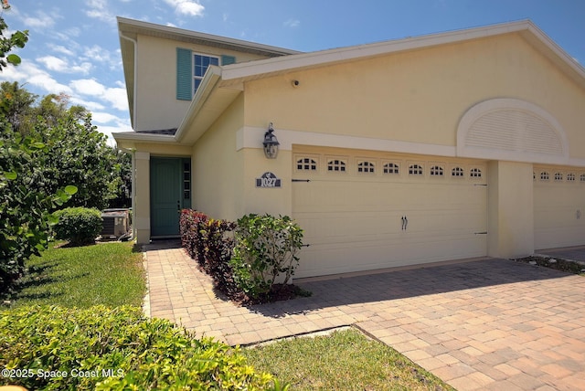 view of front facade featuring decorative driveway, a garage, and stucco siding