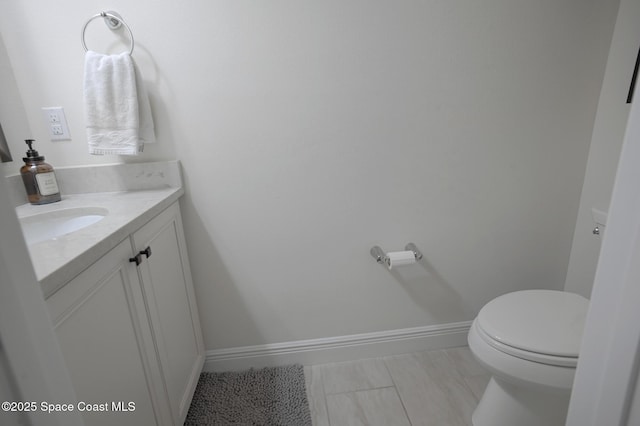 half bath featuring toilet, baseboards, and vanity
