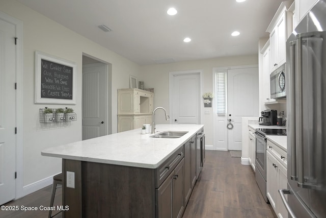 kitchen with a sink, dark wood-style floors, stainless steel appliances, recessed lighting, and an island with sink