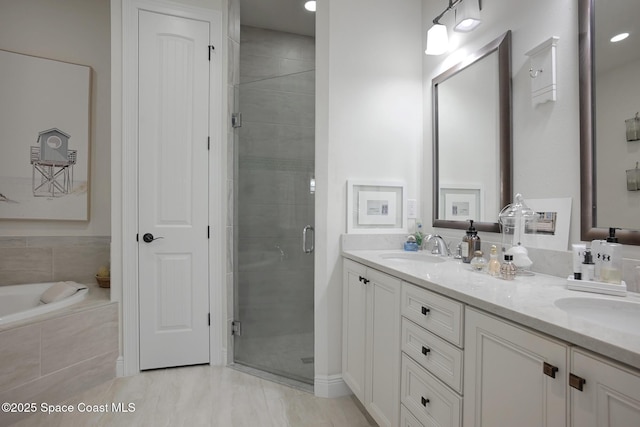 full bathroom featuring double vanity, a sink, tiled tub, and a stall shower