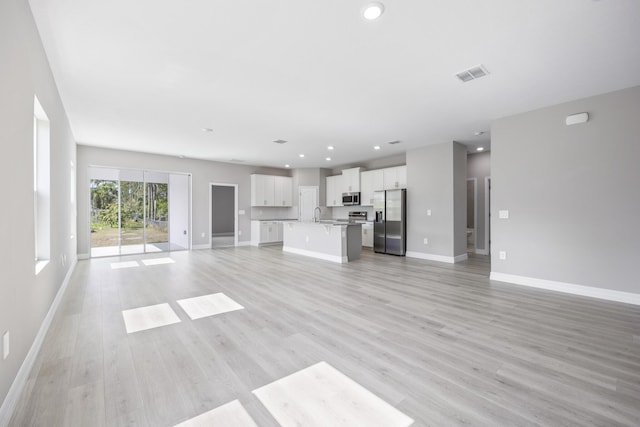 unfurnished living room featuring a sink, recessed lighting, baseboards, light wood-type flooring, and visible vents