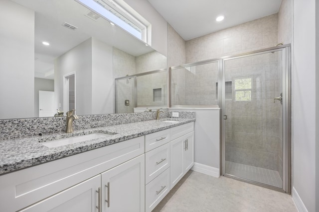 full bath featuring visible vents, a sink, double vanity, and a shower stall
