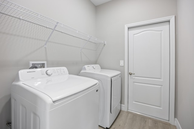 washroom featuring independent washer and dryer, laundry area, baseboards, and light wood-type flooring