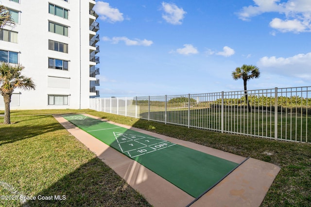 view of home's community featuring shuffleboard, a lawn, and fence