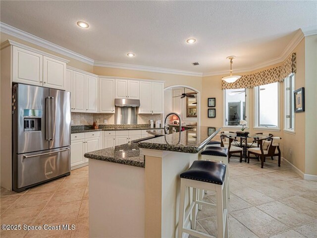 120 N White Jewel Ct, Vero Beach, FL 32963 - kitchen with white cabinetry, under cabinet range hood, and high quality fridge