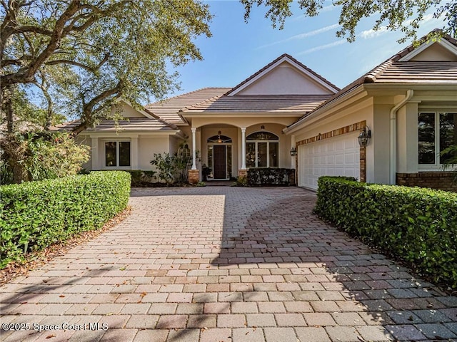 120 N White Jewel Ct, Vero Beach, FL 32963 - view of front of property with an attached garage, decorative driveway, and stucco siding