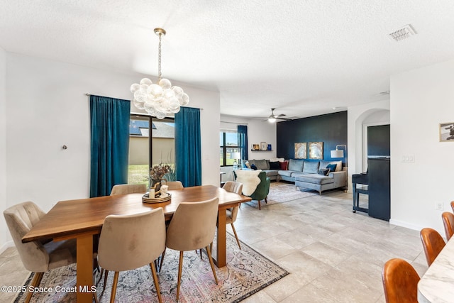 5985 Orsino Ln, Cocoa, FL 32926 - dining area featuring a chandelier, ceiling fan, a textured ceiling, arched walkways, and baseboards