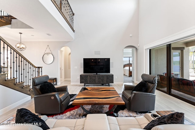 7773 Desmond Ave, Melbourne, FL 32940 - living area featuring arched walkways, a high ceiling, baseboards, stairs, and light wood-type flooring