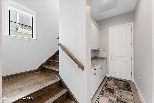 7773 Desmond Ave, Melbourne, FL 32940 - staircase featuring attic access, wood finished floors, and baseboards