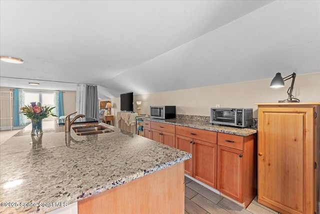 8865 Central Ave, Micco, FL 32976 - kitchen featuring stainless steel microwave, a sink, light stone counters, lofted ceiling, and a center island with sink