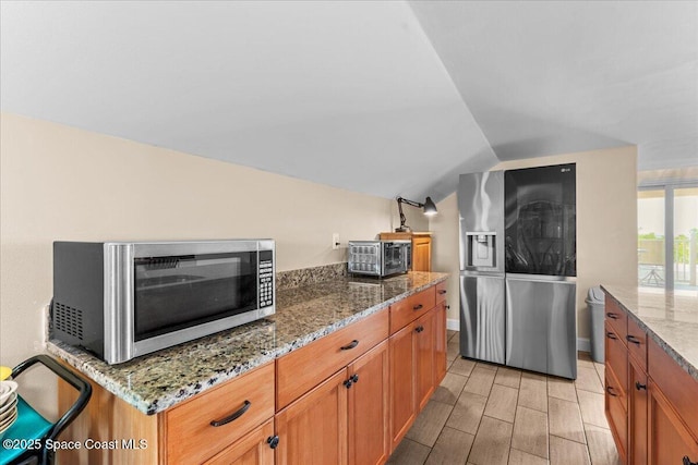 8865 Central Ave, Micco, FL 32976 - kitchen with stainless steel appliances, lofted ceiling, light stone counters, wood finish floors, and brown cabinetry